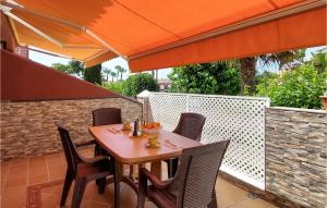 una mesa y sillas en un patio con una sombrilla naranja en Gorgeous Apartment In Chiclana De La Front, With Kitchen, en Novo Sancti Petri