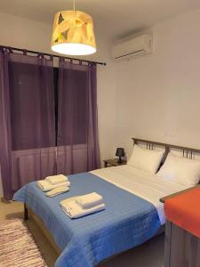 a bedroom with a blue bed with towels on it at Pinelopis House, Skala Sikamineas, Molivos, Midilli in Skála Sykaminéas