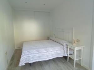 Cama en habitación blanca con mesa en Acogedor apartamento a 5 minutos de Sanxenxo, en Pontevedra