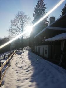 a snow covered sidewalk next to a building with the sun shining at Chata z Widokiem in Międzybrodzie Bialskie