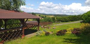 a garden with a gazebo and benches in the grass at Domki WiliCamp in Polańczyk