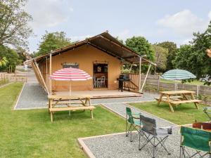 a small tent with a picnic table and two umbrellas at Tilly Bob Lodge in Llandudno