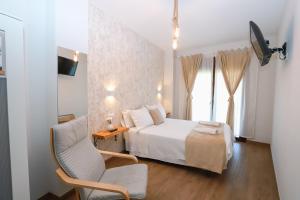 a bedroom with a white bed and a chair at Villa Galicia in Caldas de Reis