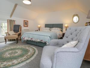 een slaapkamer met een bed, een bank en een stoel bij The Cottage in Highbridge