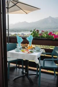 una mesa blanca con 2 sillas y una sombrilla en el balcón en Marienhof Apartments en Drobollach am Faakersee