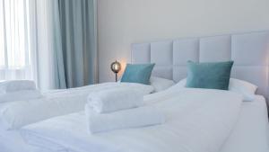 um quarto branco com 2 camas brancas com almofadas azuis em Marienhof Apartments em Drobollach am Faakersee