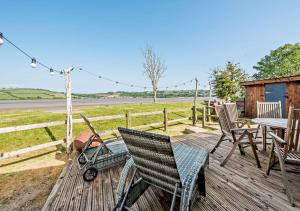 a wooden deck with chairs and a table and a stroller at Eryl in Ferryside