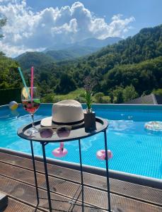 Crni Vrh的住宿－Aphrodite Hills Apartments-Stara Planina，一张带帽子的桌子和一杯葡萄酒,在游泳池畔