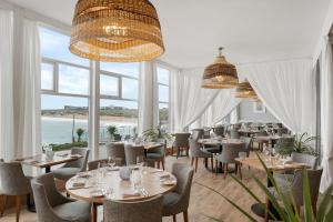 - un restaurant avec des tables et des chaises et une vue sur l'océan dans l'établissement Fistral Beach Hotel and Spa - Adults Only, à Newquay