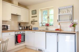 a kitchen with white cabinets and a counter top at Folly Cottage in Eastdean +5 photos