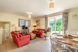a living room with red chairs and a table at Folly Cottage in Eastdean