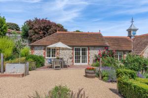 a cottage with a garden and a clock tower at Folly Cottage in Eastdean
