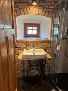 La salle de bains est pourvue d'un lavabo et d'un mur en pierre. dans l'établissement Little Cottage No.100, à Vidochov