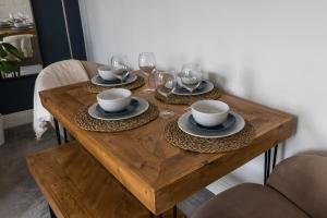 a wooden table with plates and wine glasses on it at Azure Haven - Bournemouth in Bournemouth