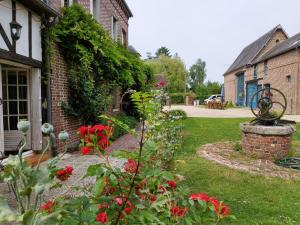 Gît' Âne Evasion في Le Bec-Thomas: حديقة بها زهور حمراء بجوار مبنى