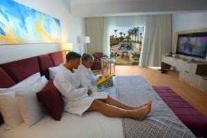 two people sitting on a bed in a hotel room at Stella Beach Resort & Spa, Makadi Bay in Hurghada