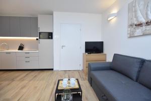 a living room with a blue couch and a kitchen at Apartment Palcic in Primošten