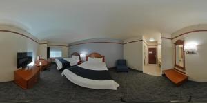 a hotel room with two beds and a television at Budget Host Inn and Suites Cameron in Cameron
