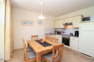 cocina con mesa de madera con sillas y nevera en Altes Wasserwerk App 20, en Wustrow 21 fotos más
