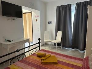 1 dormitorio con 1 cama, TV y sillas en B&B La Perla, en Vasto