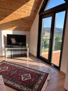 a living room with a tv and a large window at Orman ile iç içe ağaç ev in Ula