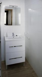 Baño blanco con lavabo y espejo en El Loft de Dulcinea: en el corazón de El Toboso., en El Toboso