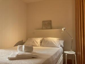 um quarto com uma cama com lençóis brancos e um candeeiro em Gago Coutinho Apartment em São Jacinto