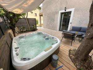 a jacuzzi tub on a deck with a patio at Maison à deux pas des plages avec jardin, terrasses et spa. in Mèze