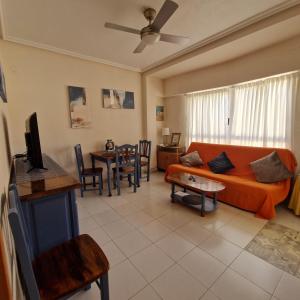 ein Wohnzimmer mit einem orangenen Sofa und einem Tisch in der Unterkunft Sol Apartment in Arenales del Sol