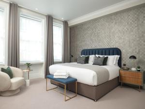 a bedroom with a king sized bed and a chair at Mayfair - Peterson House by Viridian Apartments in London