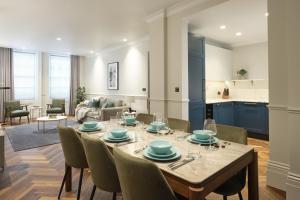 a dining room and living room with a table and chairs at Mayfair - Peterson House by Viridian Apartments in London