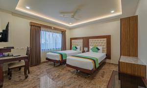 a hotel room with two beds and a desk at Treebo Aaravi Residency, 800 Mtrs From Promenade Beach in Puducherry +31 photos