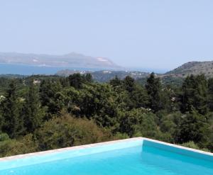 a swimming pool with a view of trees and water at Villa Aspro in Xirostérnion