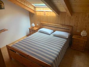 1 dormitorio con 1 cama con 2 almohadas en Appartamento Genziana, en Predazzo