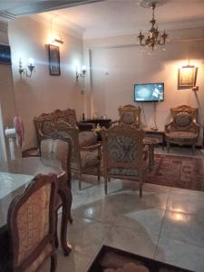 a living room with chairs and a table and a tv at Gibran residence in Kafr al Ishārah