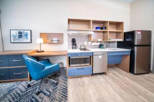 uma cozinha com uma cadeira azul e um frigorífico em Candlewood Suites Charleston – Mt. Pleasant, an IHG Hotel em Charleston