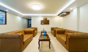 a waiting room with brown leather couches and a table at Treebo Aaravi Residency, 800 Mtrs From Promenade Beach in Puducherry