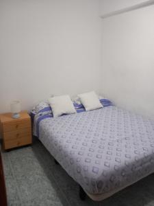 a bed with two pillows and a night stand at habitación grande en piso compartido con 2 adultos in Valencia