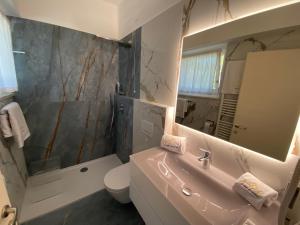 ein Badezimmer mit einem Waschbecken, einem WC und einem Spiegel in der Unterkunft Maison Eglantine in Mezzana