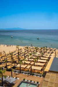 a beach with chaise lounges and palm trees and the ocean at Ayvalık Sea Long in Ayvalık