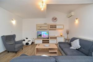 ein Wohnzimmer mit einem blauen Sofa und einem TV in der Unterkunft House Liznjan 2273 in Ližnjan