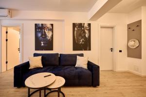 a living room with a blue couch and two posters at Infinity by Sea Apartment Beach Resort - parking in Mamaia