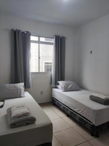 2 camas en una habitación con ventana en Apartamentos da Thay en Campina Grande