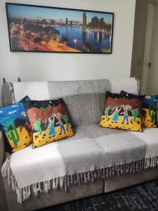 a couch with four pillows and a picture on the wall at Apartamentos da Thay in Campina Grande