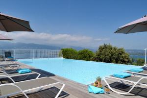 a large swimming pool with chairs and an umbrella at Résidence MARINA SERENA in Porto-Vecchio