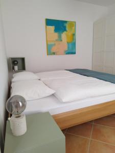uma cama com lençóis brancos e almofadas num quarto em casa pungitopo em Bedigliora