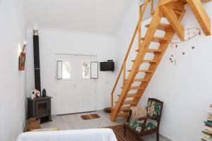 1 dormitorio con escalera de madera en una pared blanca en Típica Casa de Campo Alentejana, en Montemor-o-Novo