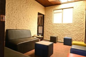 a waiting room with a leather couch and chairs at Hostal Natural in Santa Ana