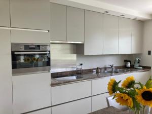 a kitchen with white cabinets and a vase of sunflowers at Vakantiewoning De Papendaler in Zutendaal