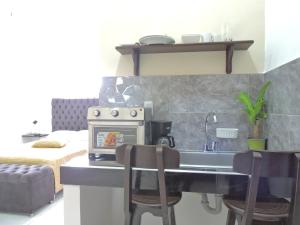 a kitchen with a stove and a sink with chairs at Apartahotel Baq Suite 44 in Barranquilla